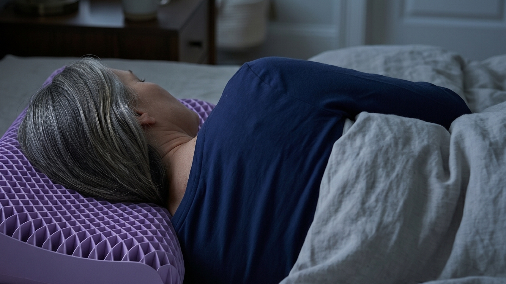 Person lying on a bed with a purple pillow, in a bedroom setting.